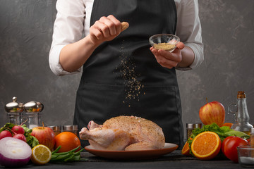 Cooking chicken by the chef, Oriental or Asian cuisine. Against the background of vegetables and fruits. Sprinkling with spices, freezing in motion.