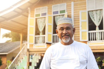 Senior man standing in front of wooden house