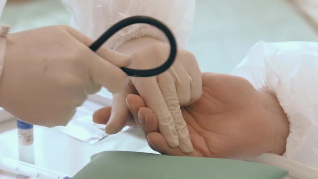 Doctor making a test kit for viral disease COVID-19 2019-nCoV. Laboratory card kit test for SARS-CoV-2 virus coronavirus. COVID-19 rapid test. Positive COVID-19. Blood sampling from a finger.
