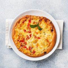 Homemade pizza tortilla with tomato and cheese on gray concrete background.
