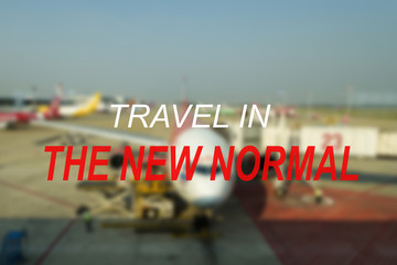 Obraz premium TRAVEL IN THE NEW NORMAL text on a blurred out forest. New normal after covid-19 pandemic. Corona Virus outbreak concept