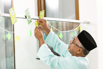 Naklejka premium Muslim man decorating home for Eid al-Fitr
