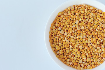 Split yellow peas in a wooden spoon on split yellow peas background.