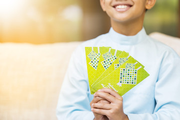 Muslim boy holding green envelopes