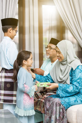 Obraz na płótnie Canvas Muslim kids receiving green envelope from grandparents during Eid al-Fitr