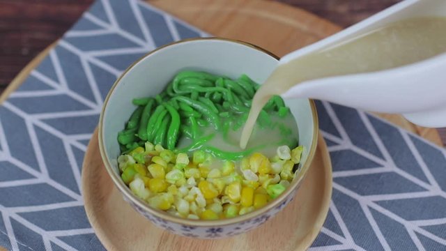 Pouring coconut syrup on rice noodles made of rice eaten with coconut cream , Lod Chong , Singapore rice noodle, made with pandan syrup in coconut milk and melon, traditional Thai desserts in Thailand