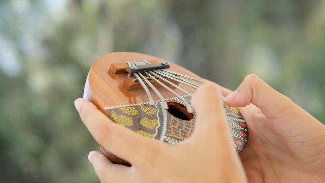 girl playing kalimba, also known as a thumb piano or mbira. African trdicional meditating 
instrument.