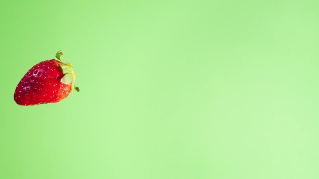 4K stop motion video of a fresh strawberry passing through the frame with green background. Straberry screensaver. Summer  fruit animation