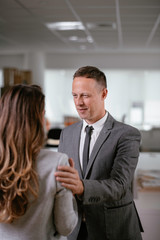 Businessman and businesswoman in office. Young woman and man flirting in office.