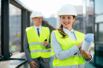 Portrait of businesswoman in factory. Young female architect with helmet in suit.	