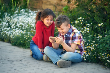 Enthusiastic siblings use their smartphones for entertainment . Children and modern technologies