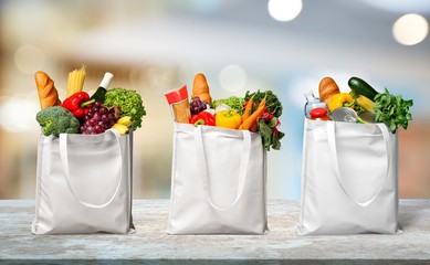 Three white shopping bags with different food, fruits and vegetables