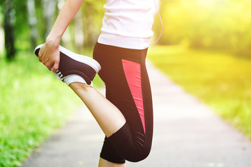 young fitness woman runner stretching legs before run on grass