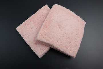 Pink slice of bread on a black background