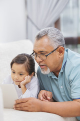 Grandfather and granddaughter using a laptop