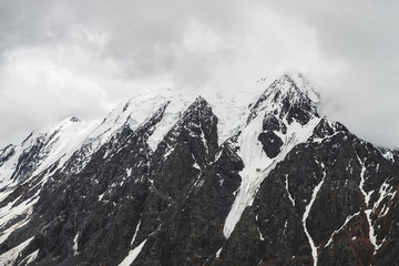 Atmospheric minimalist alpine landscape with massive hanging glacier on snowy mountain peak. Big balcony serac on glacial edge. Low clouds among snowbound mountains. Majestic scenery on high altitude.