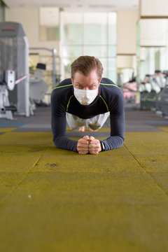 Face Of Young Man With Mask Doing Plank Position On The Floor At Gym During Corona Virus Covid-19