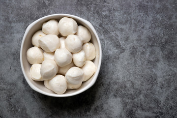Boiled fish balls in white bowl on black marble table with copy space; top view
