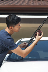 Man cleaning windshield wiper of his car - obrazy, fototapety, plakaty