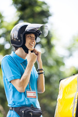 Naklejka premium Food delivery man fastening helmet belt