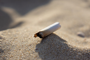 Cigarette butt in the sand. Human pollution
