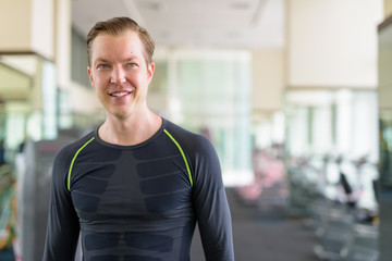 Portrait of happy young handsome man thinking at the gym during covid-19