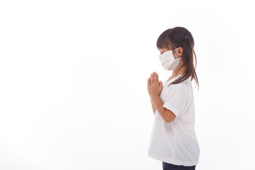 Asian girl wearing mask for protect pm2.5 and coronavirus Covid-19.Stay at home praying to GOD.Online church worship in sunday.Little asian girl hand praying at home.Social distancing.