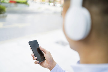 Man listening to music on headphones while using his phone