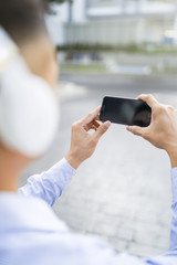 Man listening to music on headphones while using his phone