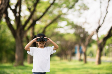 Naklejka premium Happy child girl playing with binoculars. explore and adventure concept