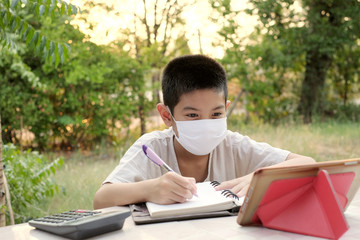 Thai children sit online learning at the front garden.