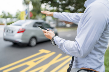 Man holding a mobile phone while hailing for a ride