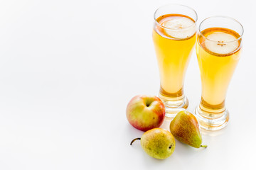 Glasses of beer with apple and peer on white table copy space