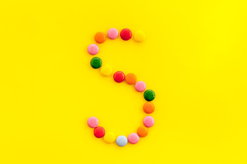 Letter S - alphabet made with sweets on yellow from above