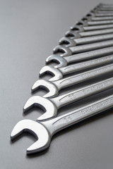 Spanners. Many wrenches. Grey background. Set of wrenches in different sizes on grey background....