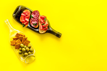 Wine appetizer on bottles as dinnerware on yellow table top view copy space