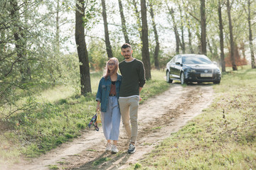 Fototapeta premium Couple walking in the woods, in the background you can see the car