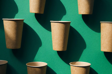 Eco friendly craft paper cups on green background.