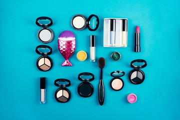 Flat lay a variety of cosmetics and accessories on a turquoise background.