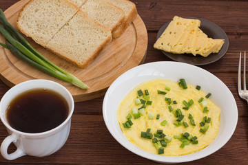breakfast omelet tea cheese bread and onion on a wooden table
