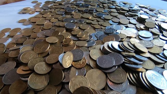 White and yellow coins fall to surface of coins close-up.