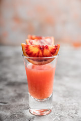 Strong red cocktail in shots on the rustic background. Selective focus. Shallow depth of field.