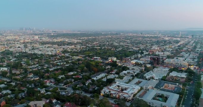 Aerial, reverse, drone shot panning over Laurel Avenue overlooking houses and empty streets, Downtown Los Angeles in the background, during dusk in California, USA - Quiet city due to COVID-19