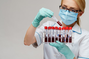 medical doctor nurse woman wearing protective mask and gloves - holding rack with virus blood tests