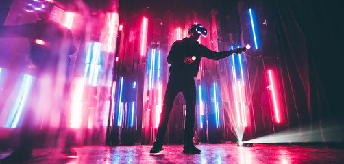 Man wearing VR headset in dark space with neon light lamps. Bottom view .
