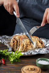 Hands of a cook woman are cutting baked meat, closeup, shallow depth of field, selective focus. Delicious homemade food concept.