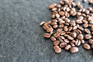 Coffee beans on black stone background. Group of coffee beans on the side of image and copy space for text.