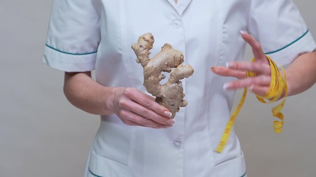 nutritionist doctor healthy lifestyle concept - holding ginger root and measuring tape