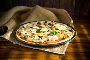 raw pizza with assorted filling in a metal form