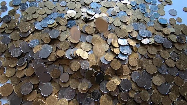 Person picks up handful of coins in hand and throws it over coins on table.